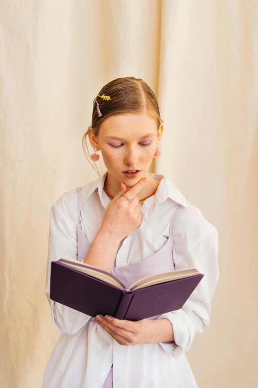 a girl is wearing white and reading a book