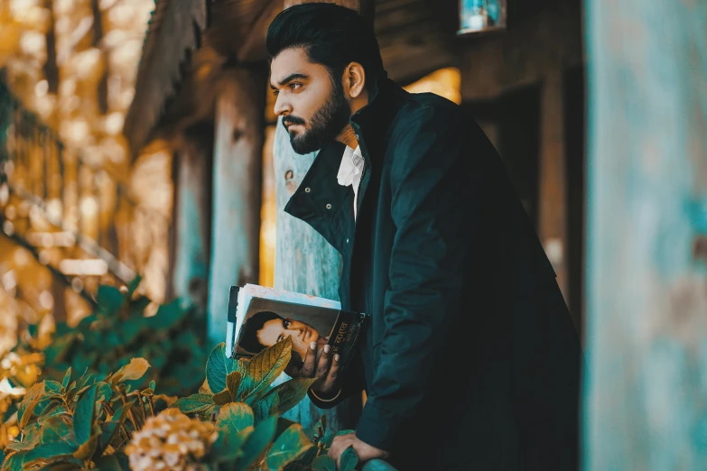 man in coat standing next to a bunch of bushes