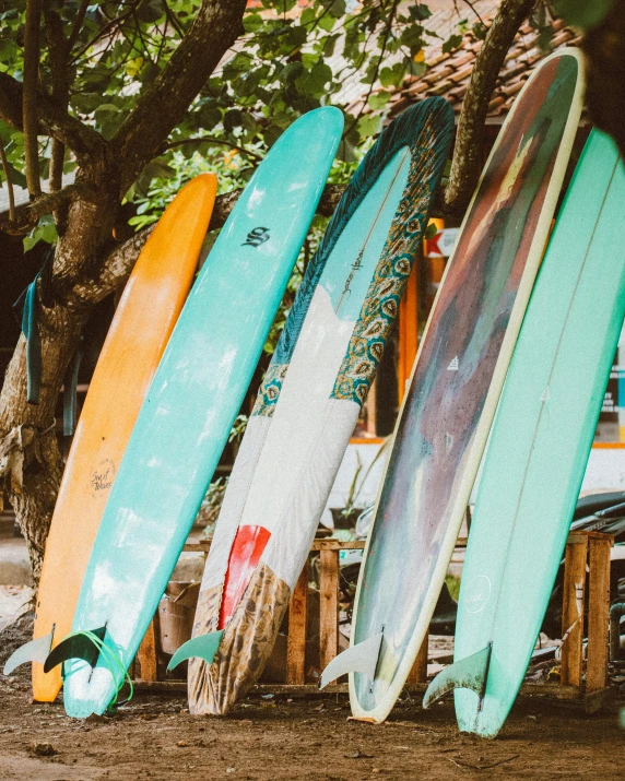 several surfboards lined up against the side of a wooden bench