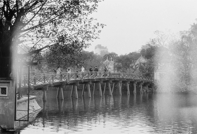 a bridge with trees and people on it on the water