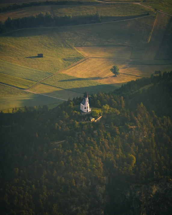 an aerial view of a church in the middle of some green hills