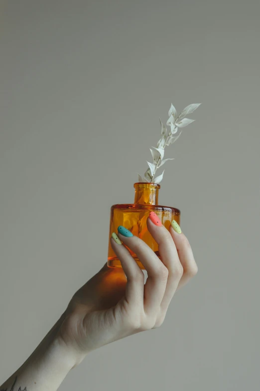 the woman's hand is holding a jar with a flower inside