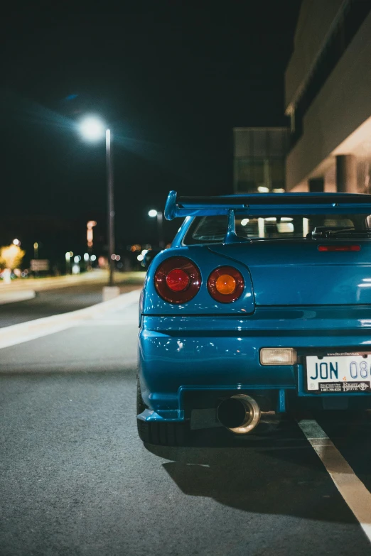 a blue car is parked at night in a parking lot