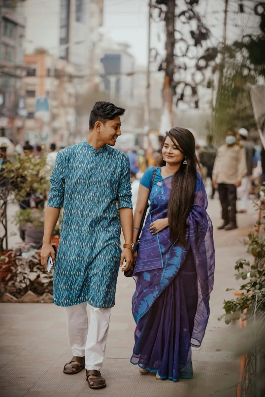 man and woman walking down the street with tall buildings in the background