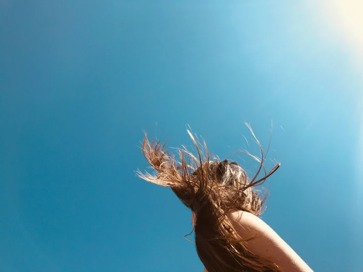 a woman is looking up at the sky and she's blowing her hair
