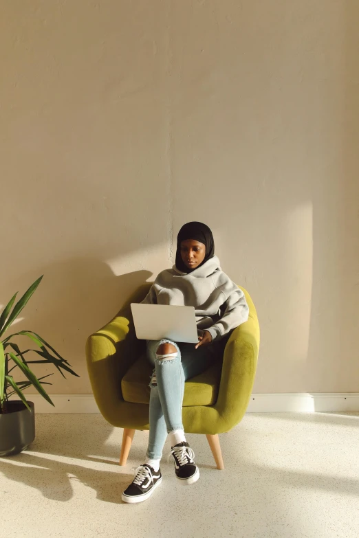 a little child sitting on a yellow chair using a laptop