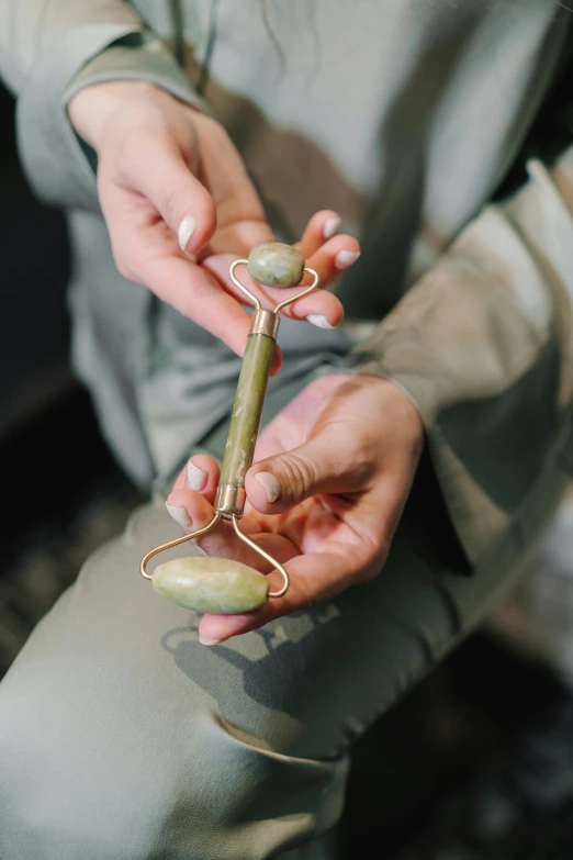 hands holding a small ss and green metal object