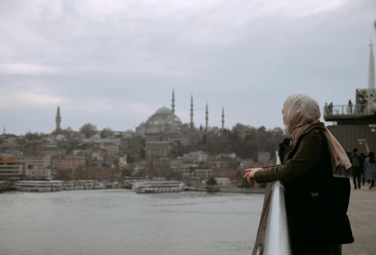 the woman looks over the water from a pier