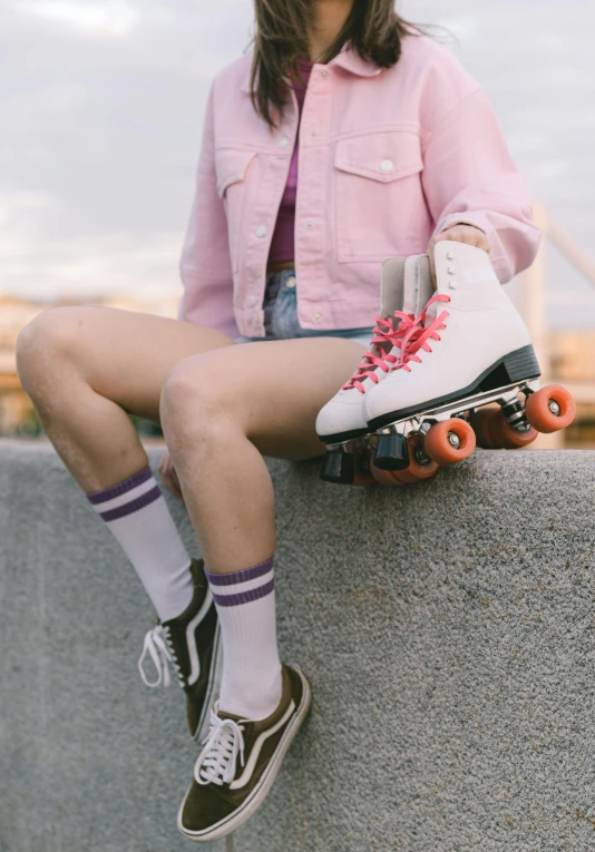 a little girl wearing pink and blue shorts, holding two skateboards