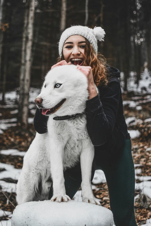 woman holding and hugging a white dog in the snow