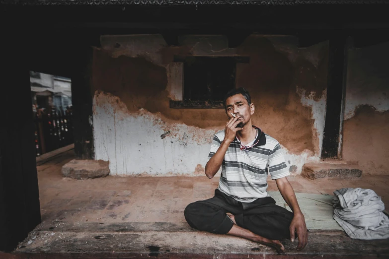 a man sitting on the ground and brushing his teeth