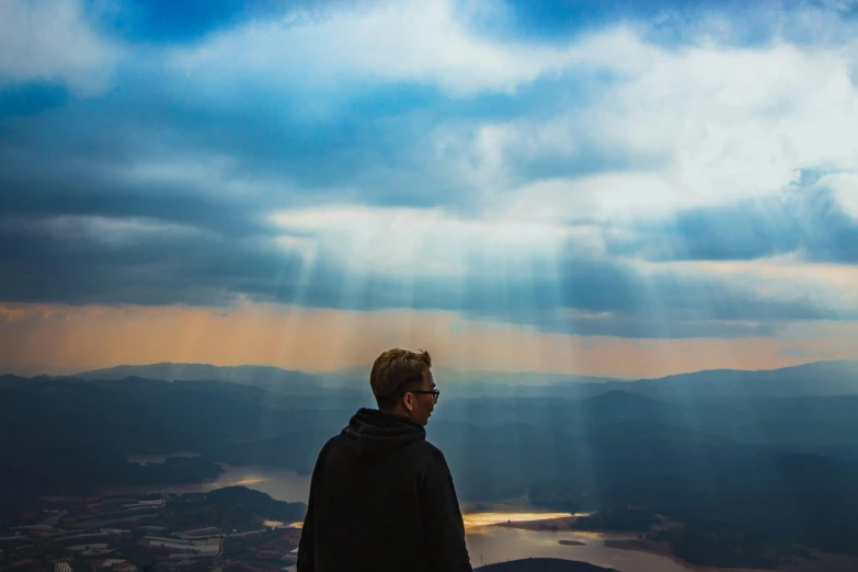 a man standing at the top of a hill with his head in the clouds