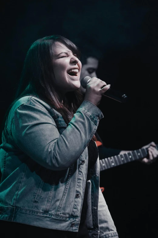 a woman singing with an electric guitar and a microphone to her side