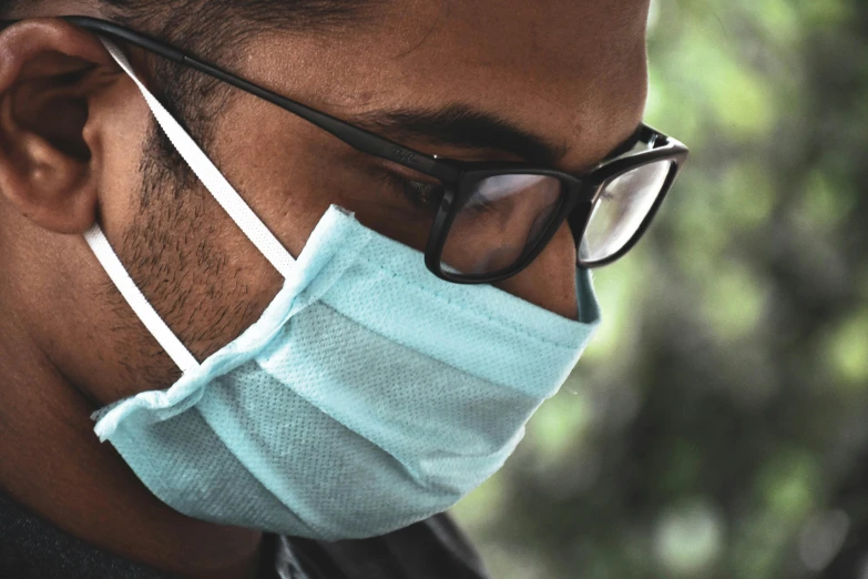 a man wearing a surgical face mask with glasses