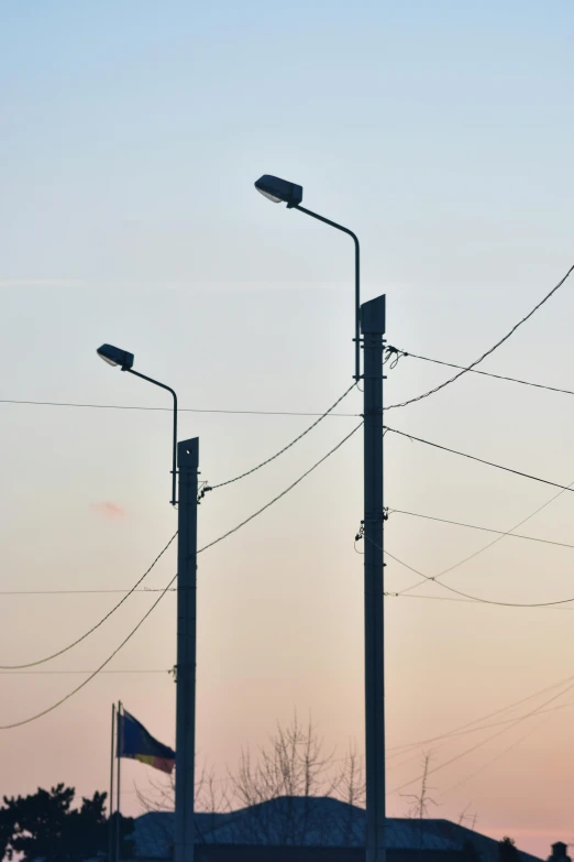 street lights on a pole are silhouetted against a pink sky