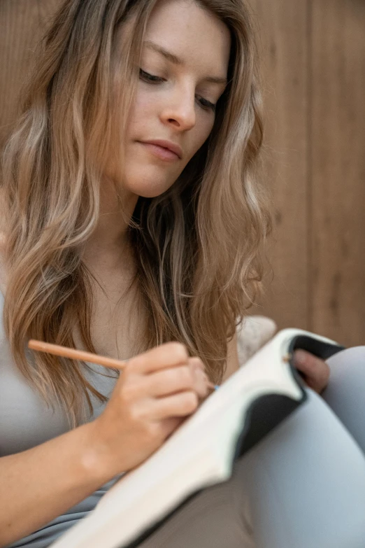 woman laying on couch writing on paper while looking down at a note pad