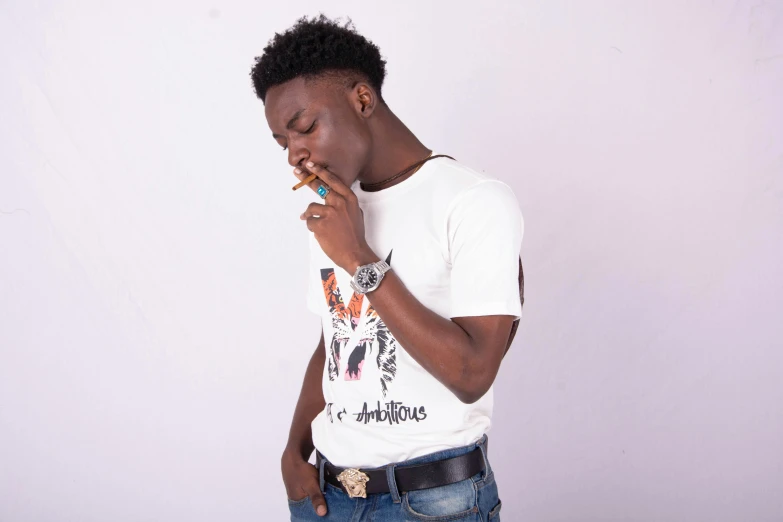 a young man smokes a cigarette while wearing a white shirt