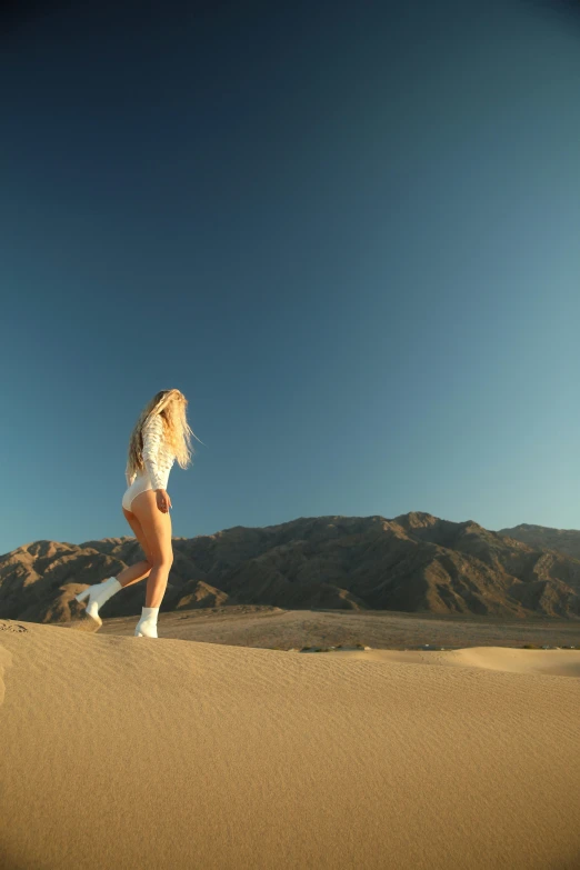 a girl walking across the desert looking to soing