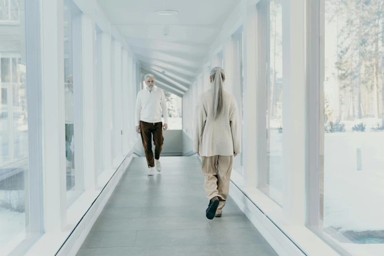 two people in white clothes walking down a corridor