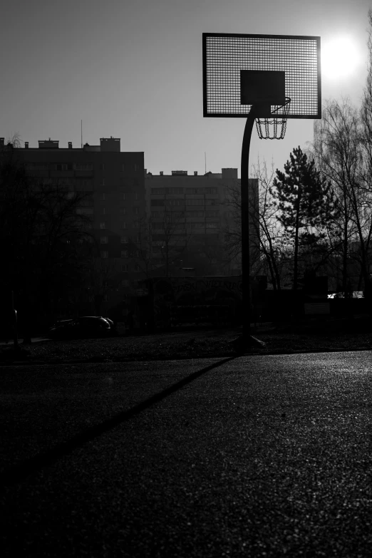 a black and white picture of a basketball court in the evening