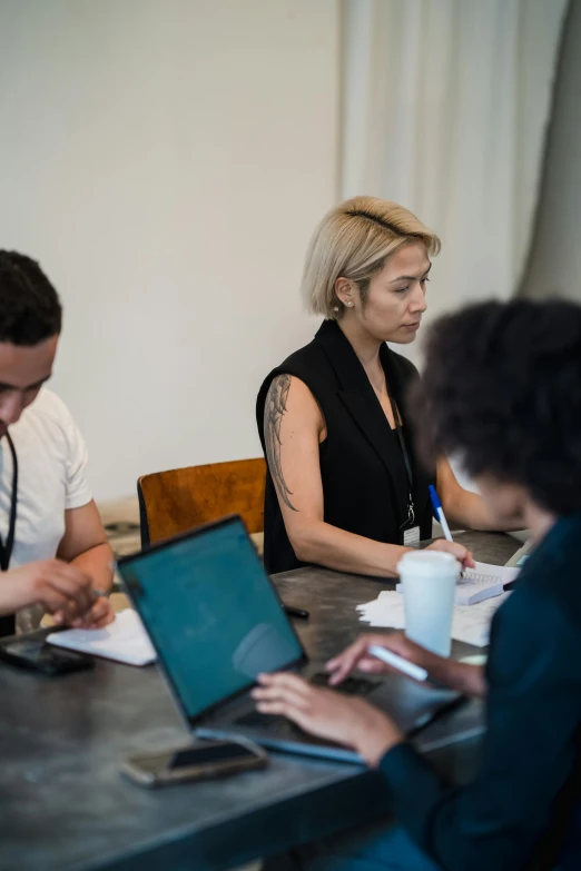 two women sitting at a table with one of them using a laptop computer