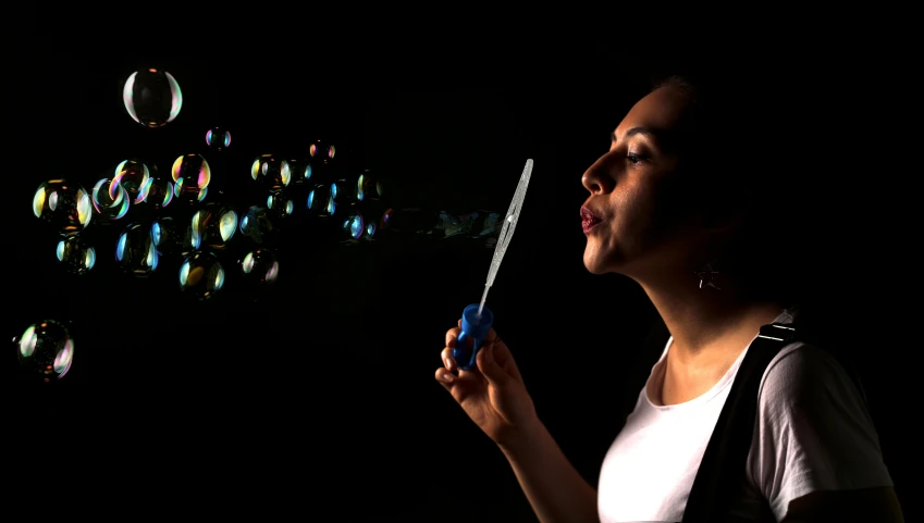 a woman holding a pair of scissors in her hand and soap bubbles coming out of it
