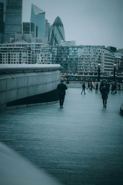 a person in black with an umbrella walking over a walkway