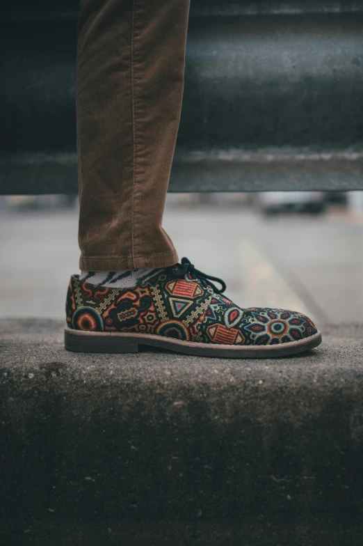 a person wearing patterned shoes stands on concrete