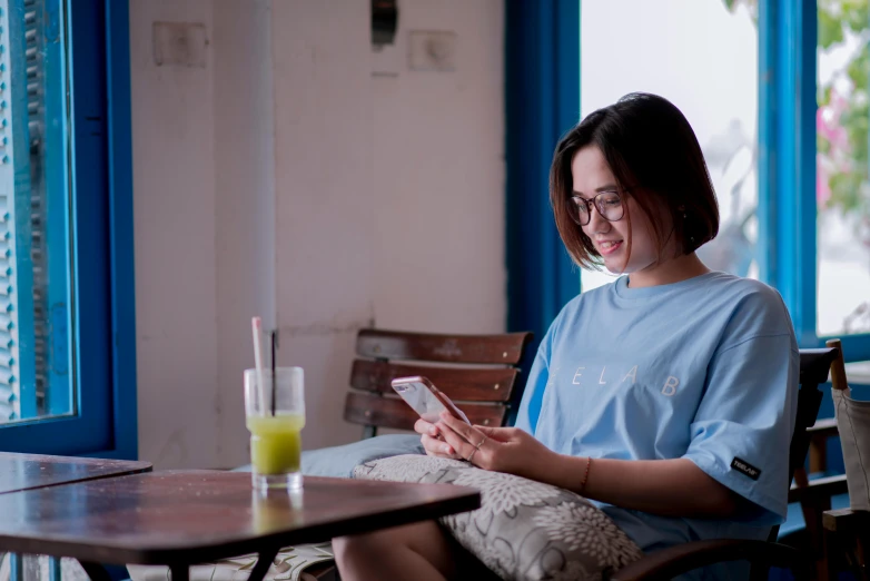 a woman holding a smart phone in her hands while sitting down