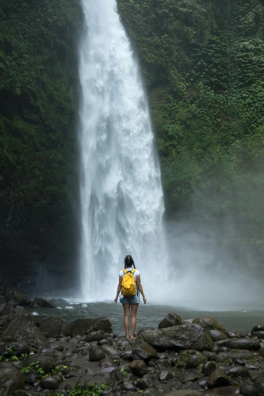 a person standing at the base of a waterfall