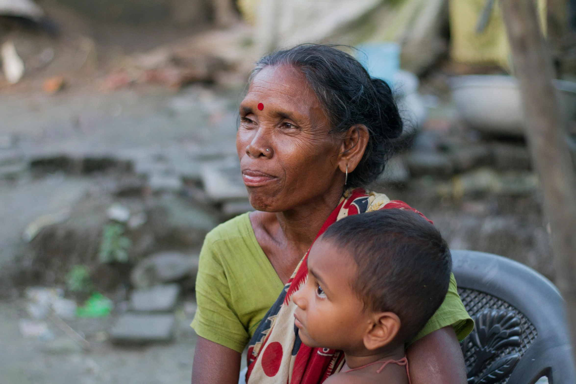 an indian woman holding a child sitting next to her