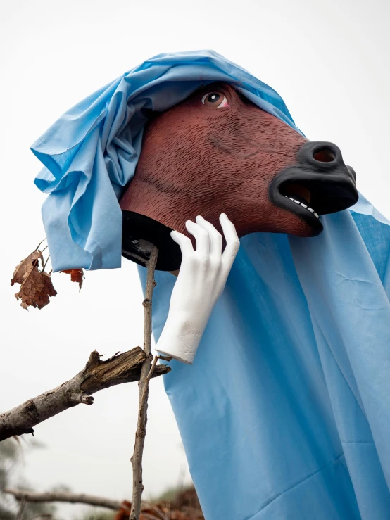 a fake horse's head is on the phone, wearing a sheet