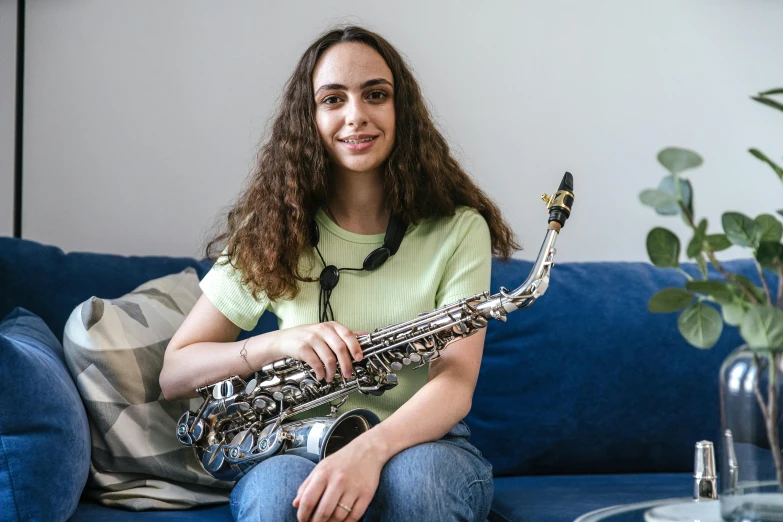 a person that is holding a saxophone sitting on a couch