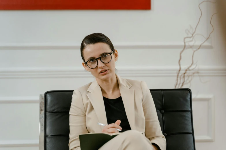 a business woman sitting on a chair in front of a red abstract painting
