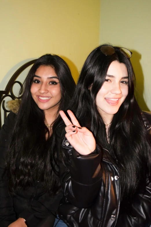 two women sitting on a couch making the peace sign