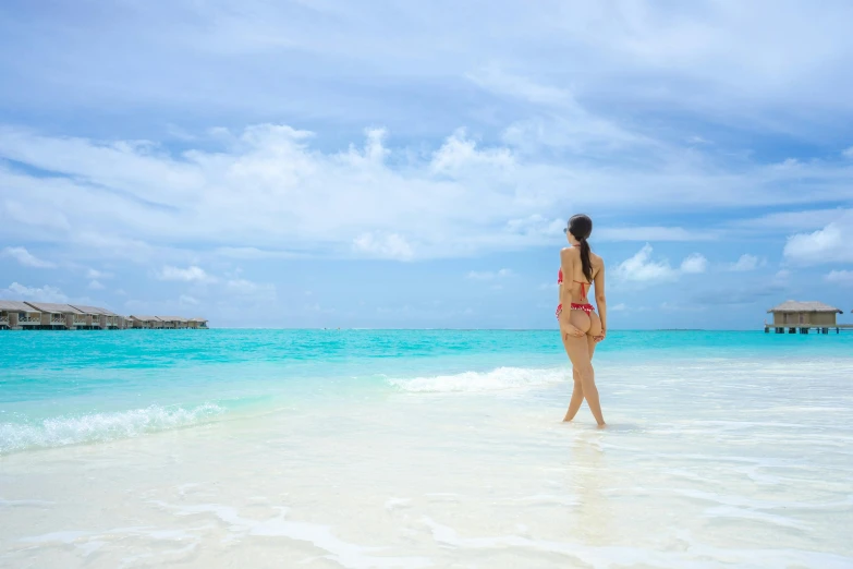 a woman walking along the beach with the water in the background