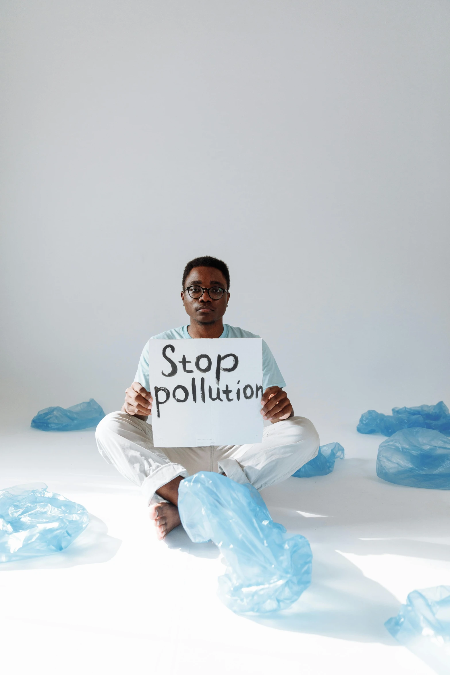 a person in glasses sitting on a floor holding up a sign