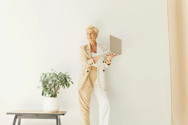 an older woman leaning against the wall while looking at a computer