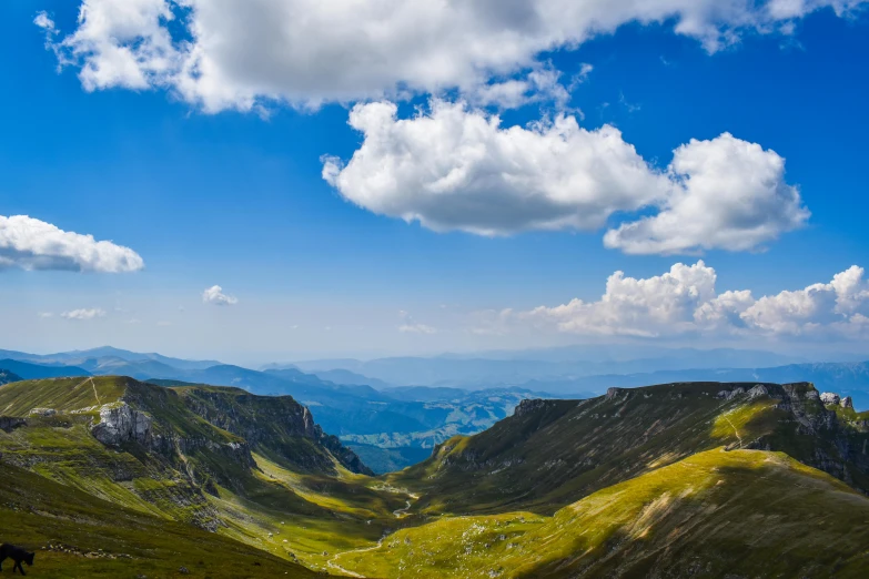 a green valley with a sky filled with clouds