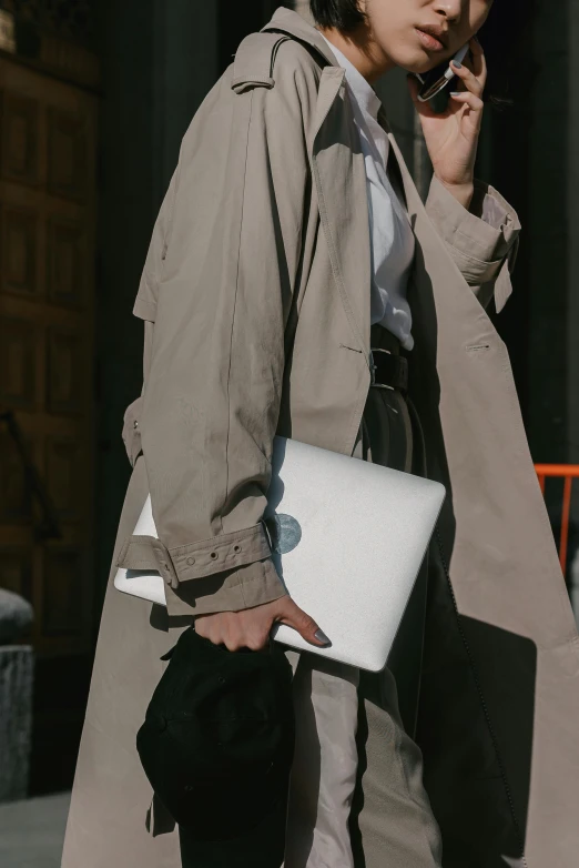 a man in beige coat on cellphone on sidewalk