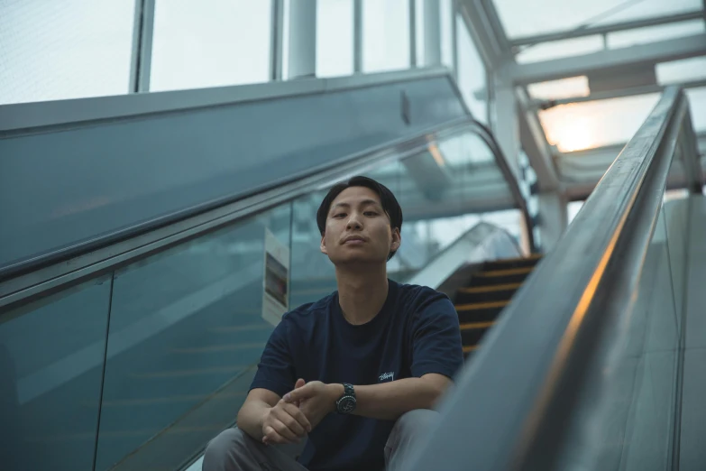 young man sitting on an escalator looking at the sky