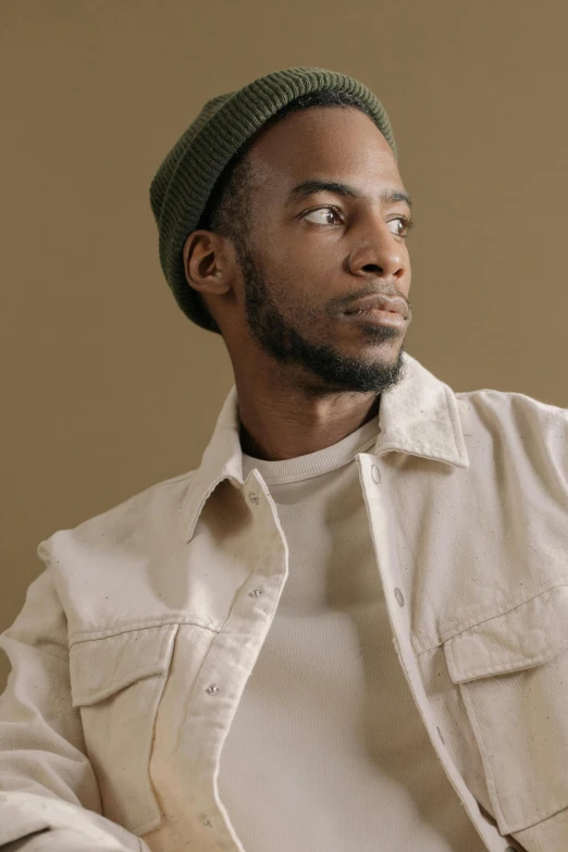 a man with a tie and sweater, wearing a green hat