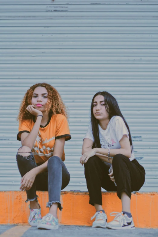 two girls sit with their arms folded out next to each other