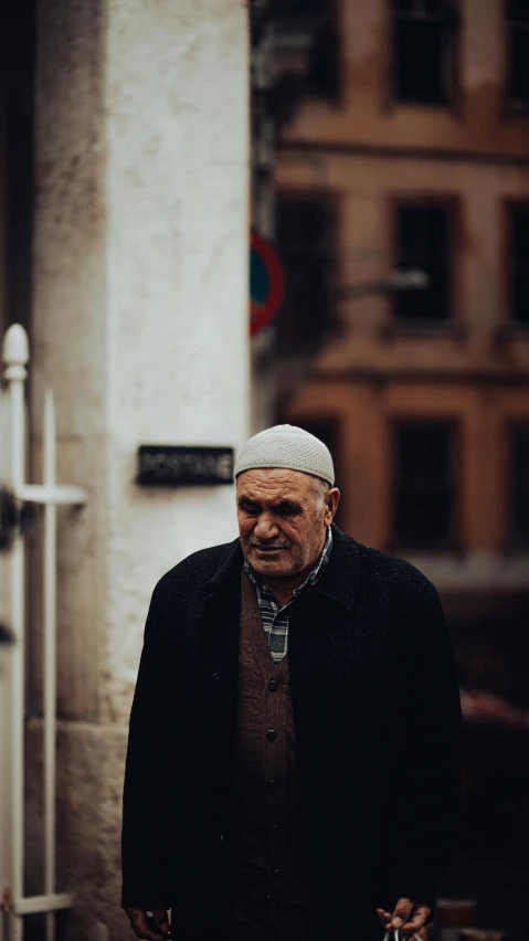 old man standing on sidewalk near building in daylight