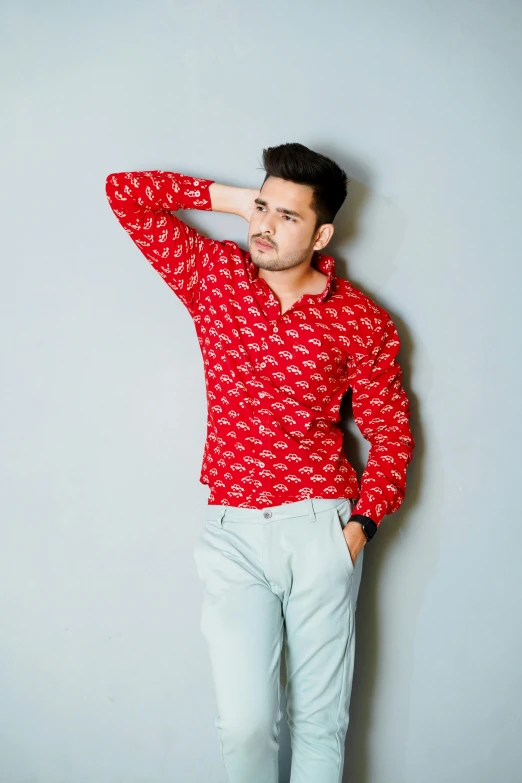 a man in red shirt standing against grey wall