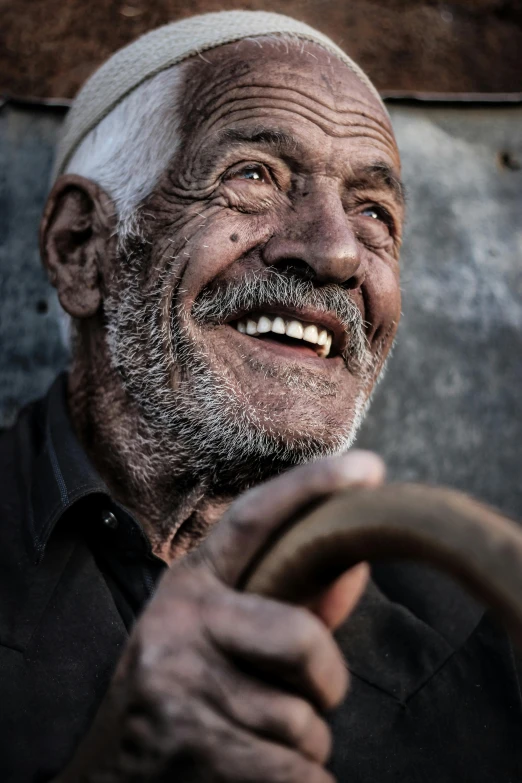 a smiling old man is holding on to the steering wheel