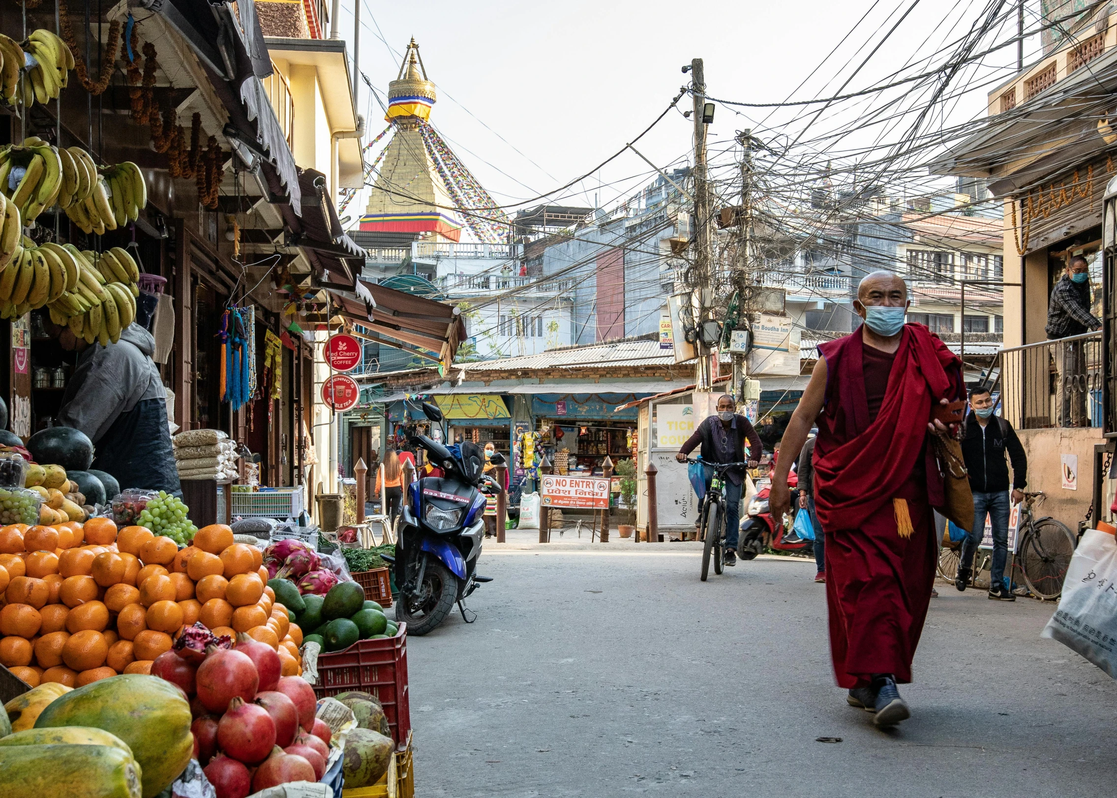 a monk walking down a street between stores