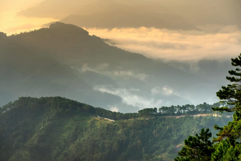 a view of a mountain range and the sun peeking through the clouds