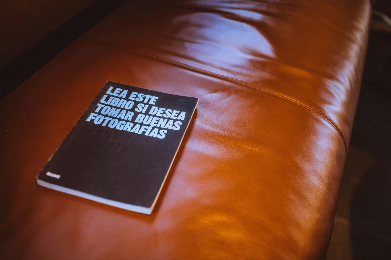 a black book with french words on it sits on a leather couch