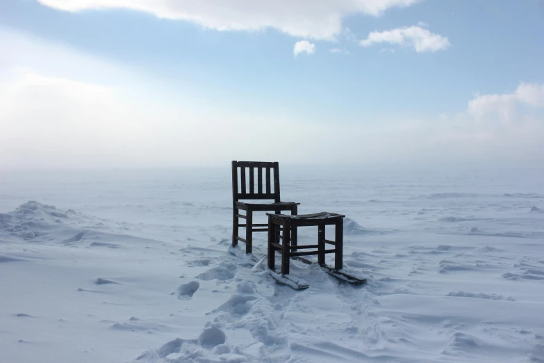 two chairs sitting on the snow, one facing forward